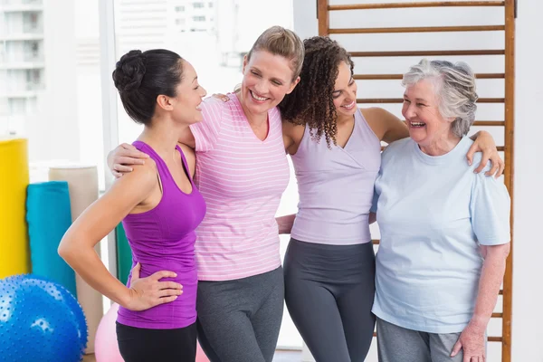 Female friends standing arms around in gym — Stock Photo, Image