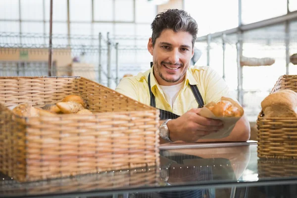 Server sorridente in grembiule con pane in mano — Foto Stock