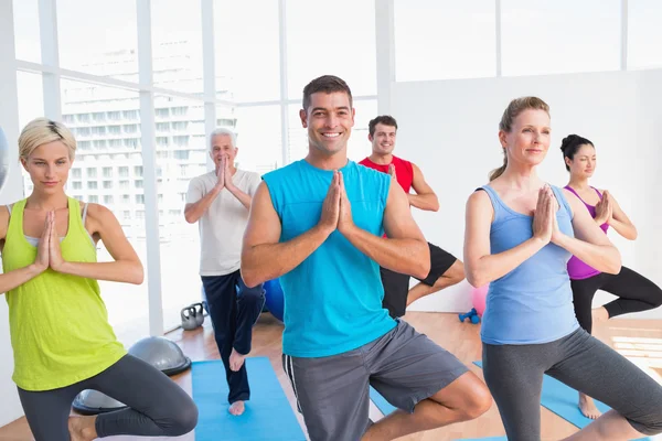 Människor som utövar tree pose i fitnesstudio — Stockfoto