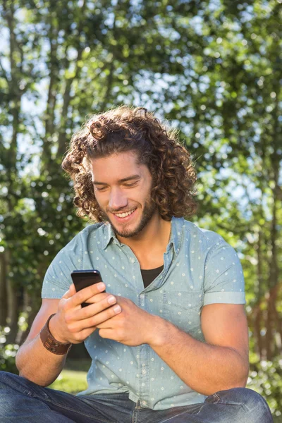 Jongeman met smartphone in het park — Stockfoto