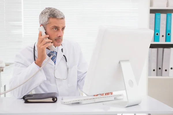 Doctor phoning and using computer — Stock Photo, Image