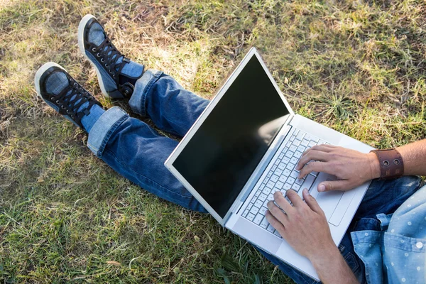 Jeune homme utilisant un ordinateur portable dans le parc — Photo