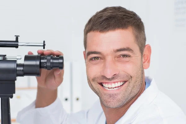 Happy optician using slit lamp in clinic — Stock Photo, Image