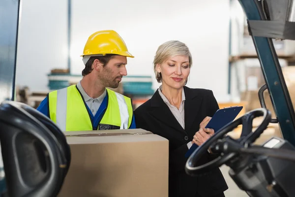 Magazijnbeheerder praten met heftruck chauffeur — Stockfoto