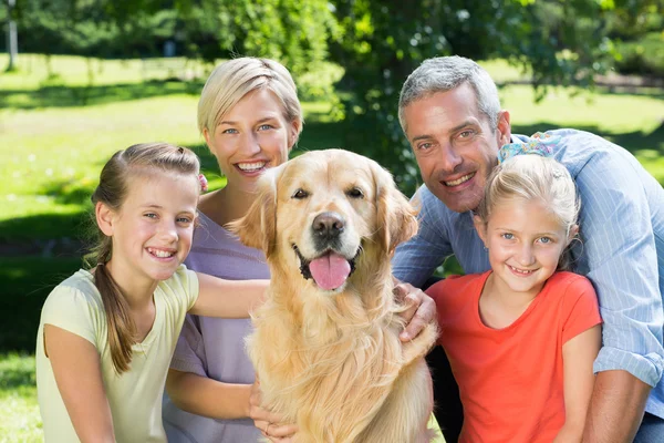 Familia sonriendo a la cámara con perro — Foto de Stock