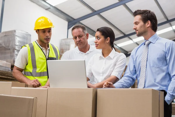 Warehouse managers and worker looking at laptop — Stock Photo, Image