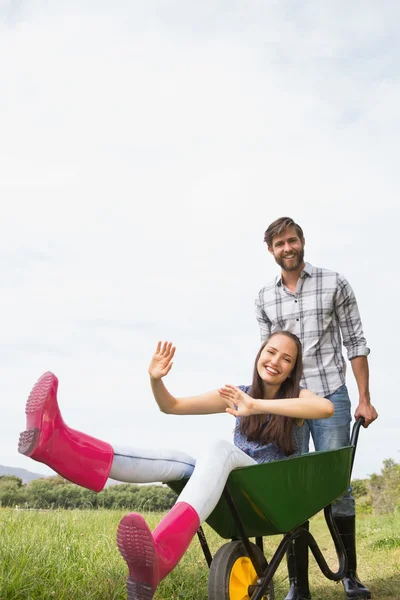 Man pushing girlfriend in wheelbarrow — Stock Photo, Image