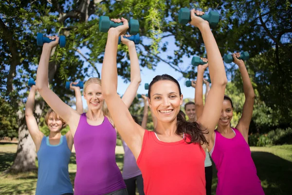 Fitness group lifting hand weights in park — Stock Photo, Image