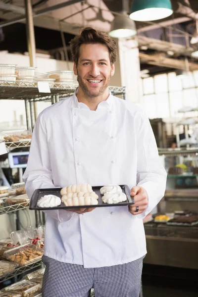 Smiling baker holding meringue tray — Stock Photo, Image