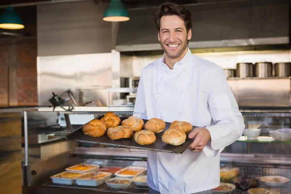 Smiling baker holding tray with bread — Stock Photo, Image