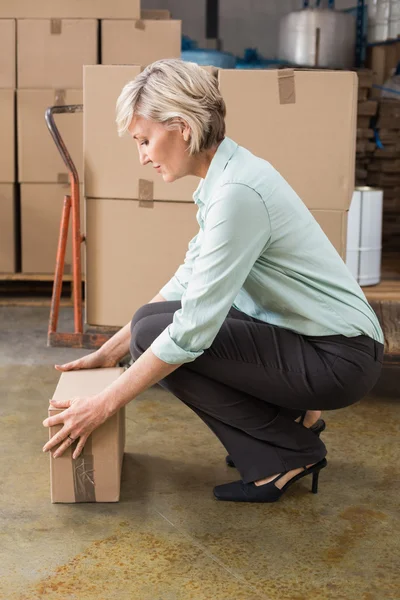 Warehouse manager picking up cardboard box — Stock Photo, Image