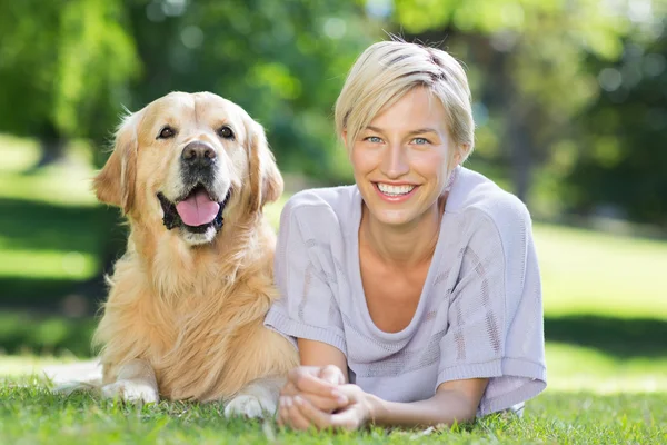Blonde liggen met haar hond in park — Stockfoto