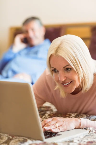 Szczęśliwy dojrzała blondynka za pomocą laptopa na łóżku — Zdjęcie stockowe