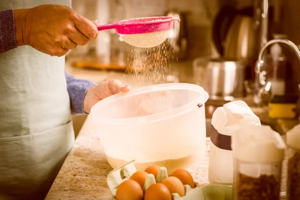 Woman sieving flour into bowl — Stock Photo, Image