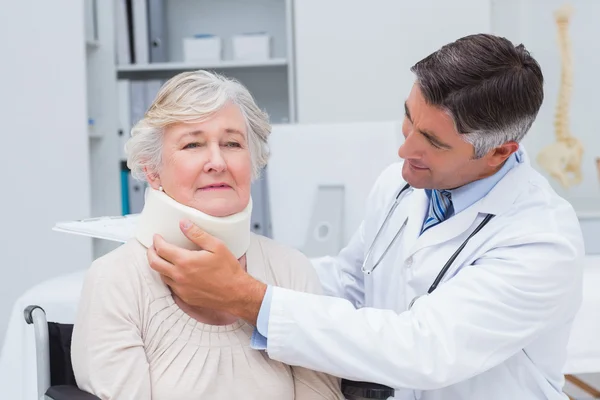 Doctor examining patient wearing neck brace — Stock Photo, Image