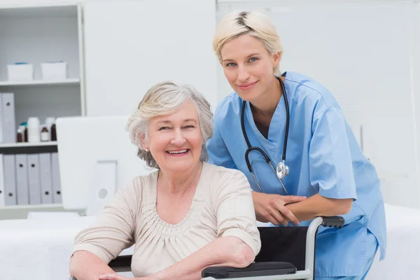 Nurse leaning on senior patients wheelchair — Stock Photo, Image