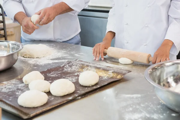 Co-workers kneading uncooked dough together — Stock Photo, Image