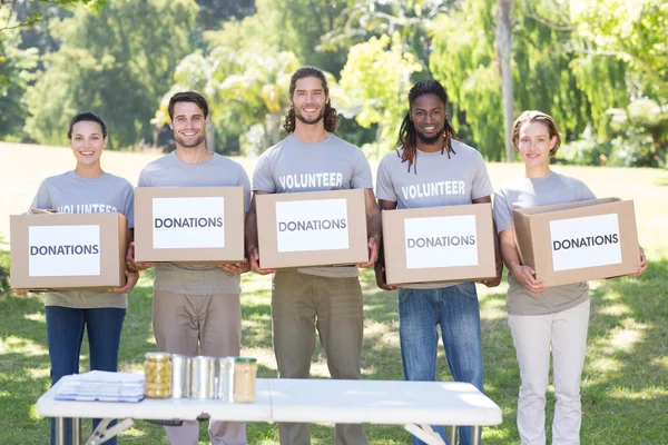 Happy volunteers with donation boxes in park — Stock Photo, Image