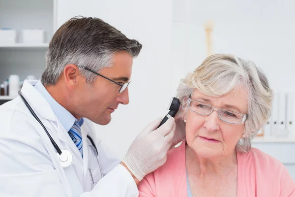 Médico examinando pacientes mujeres oído con otoscopio — Foto de Stock