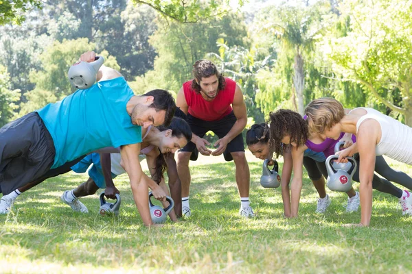 Fitness groep planking in park met coach — Stockfoto