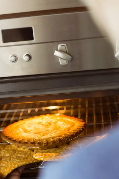 Woman taking fresh pie out of oven — Stock Photo, Image