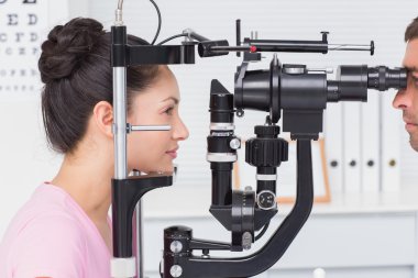 Female patient being examined by optician clipart