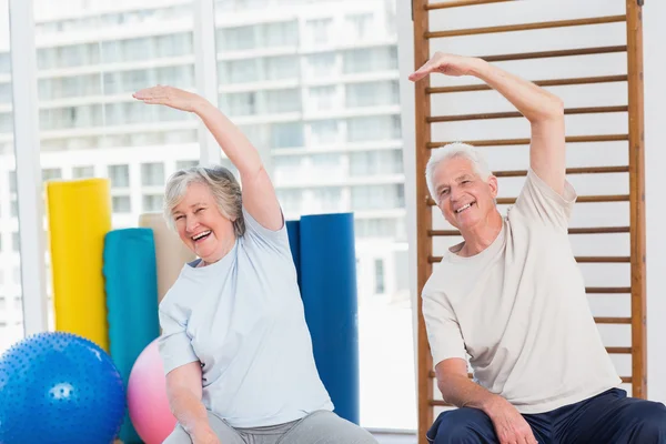 Старшая пара делает упражнения на растяжку в тренажерном зале — стоковое фото
