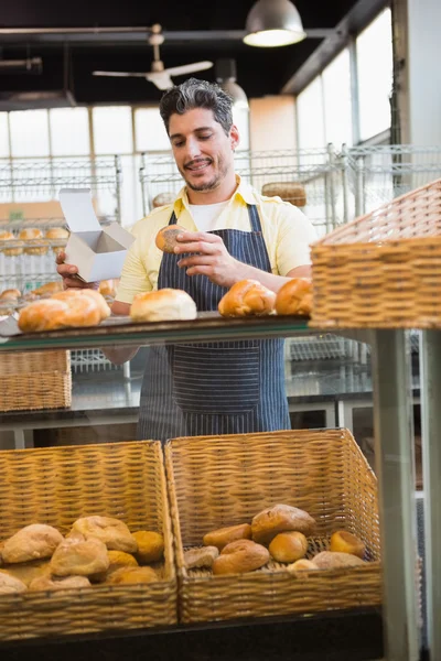 Servidor sonriente sosteniendo pan y caja —  Fotos de Stock