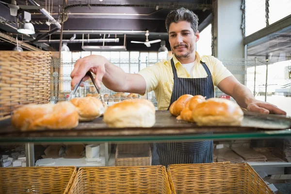 Улыбающийся официант берет хлеб щипцами — стоковое фото
