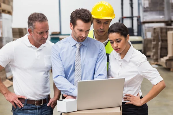 Warehouse managers and worker looking at laptop — Stock Photo, Image