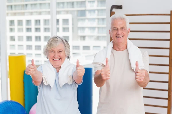 Senior couple gesturing thumbs up in gym — Stock Photo, Image