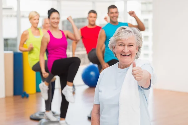 Feliz mujer mayor señalando pulgares en el gimnasio —  Fotos de Stock