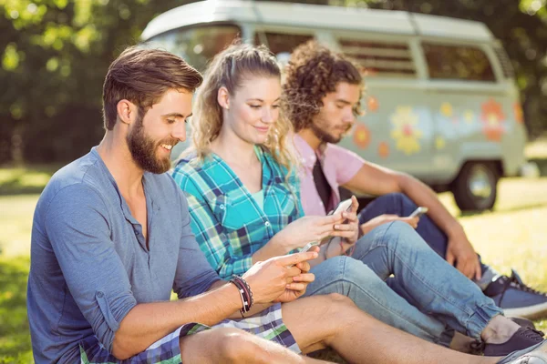 Hipster sitzen auf dem Gras und schreiben SMS — Stockfoto