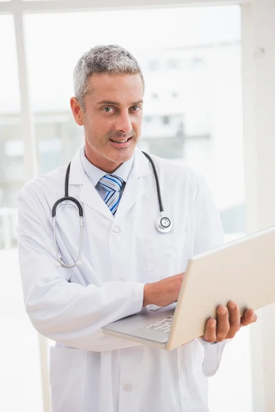 Médico usando laptop sorrindo — Fotografia de Stock