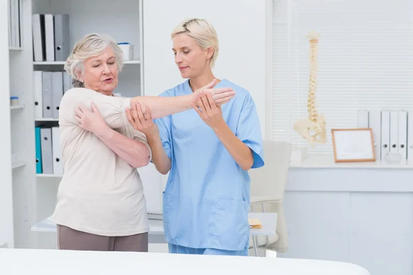 Enfermera que ayuda al paciente a levantar el brazo — Foto de Stock