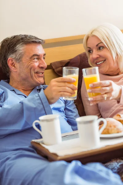 Happy mature couple having breakfast in bed — Stock Photo, Image