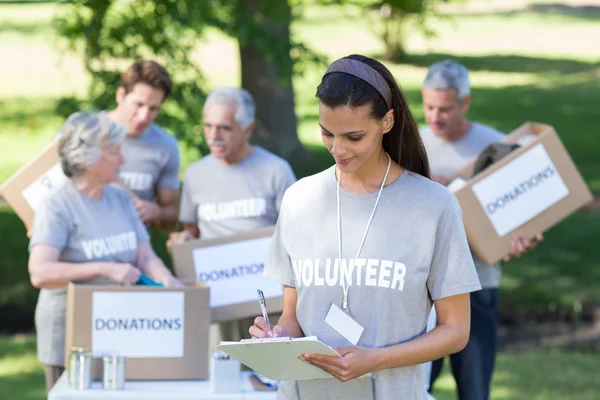 Sonriente voluntario morena escribiendo en el tablero de cifrado — Foto de Stock