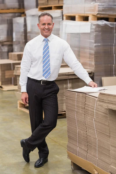 Szef uśmiechający się opierając się na stosie kartonów — Zdjęcie stockowe