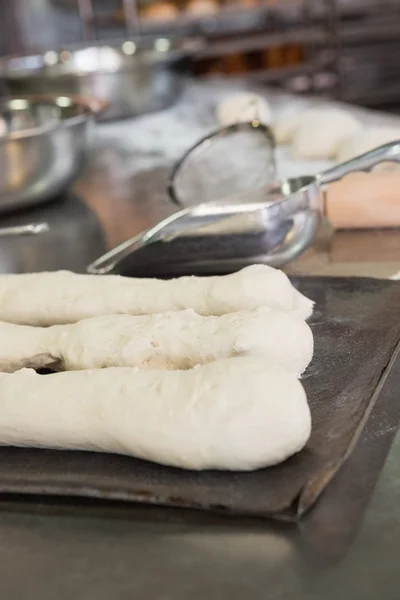 Worktop with uncooked baguettes and breads — Stock Photo, Image