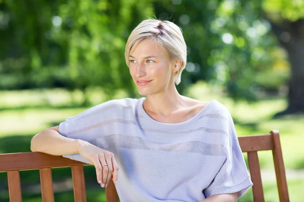 Glimlachend blonde zittend op een bankje — Stockfoto