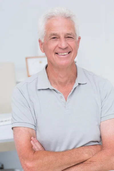 Senior man staande wapens gekruist in de kliniek — Stockfoto