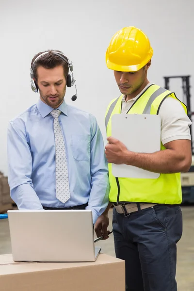Lagerarbetare och chef tittar på bärbar dator — Stockfoto