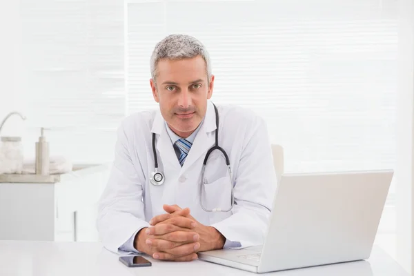 Smiling doctor sitting at his desk — Stock Photo, Image