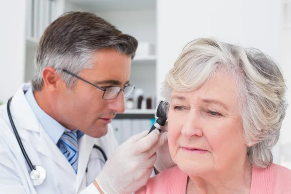 Врач осматривает ухо пациента с помощью отоскопа — стоковое фото
