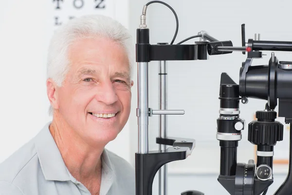 Happy senior man in front of slit lamp — Stock Photo, Image