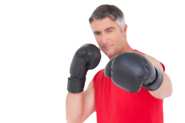 Ajuste hombre perforando con guantes de boxeo — Foto de Stock