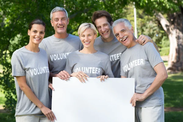 Vrijwilligers en gelukkige familie houden een blanco — Stockfoto