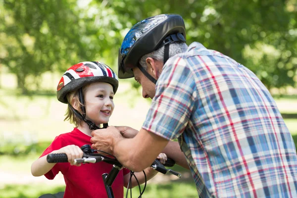 Padre attaccando i suoi figli casco da ciclismo — Foto Stock