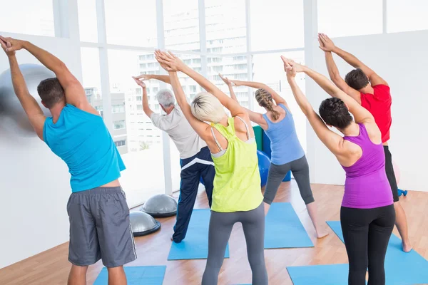 Люди, делающие упражнения на растяжку в классе йоги — стоковое фото