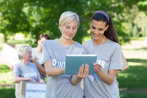 Happy volunteer friends using tablet pc — Stock Photo, Image